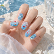 Blue koi oval press-on nails with clear water-wave details worn on a hand