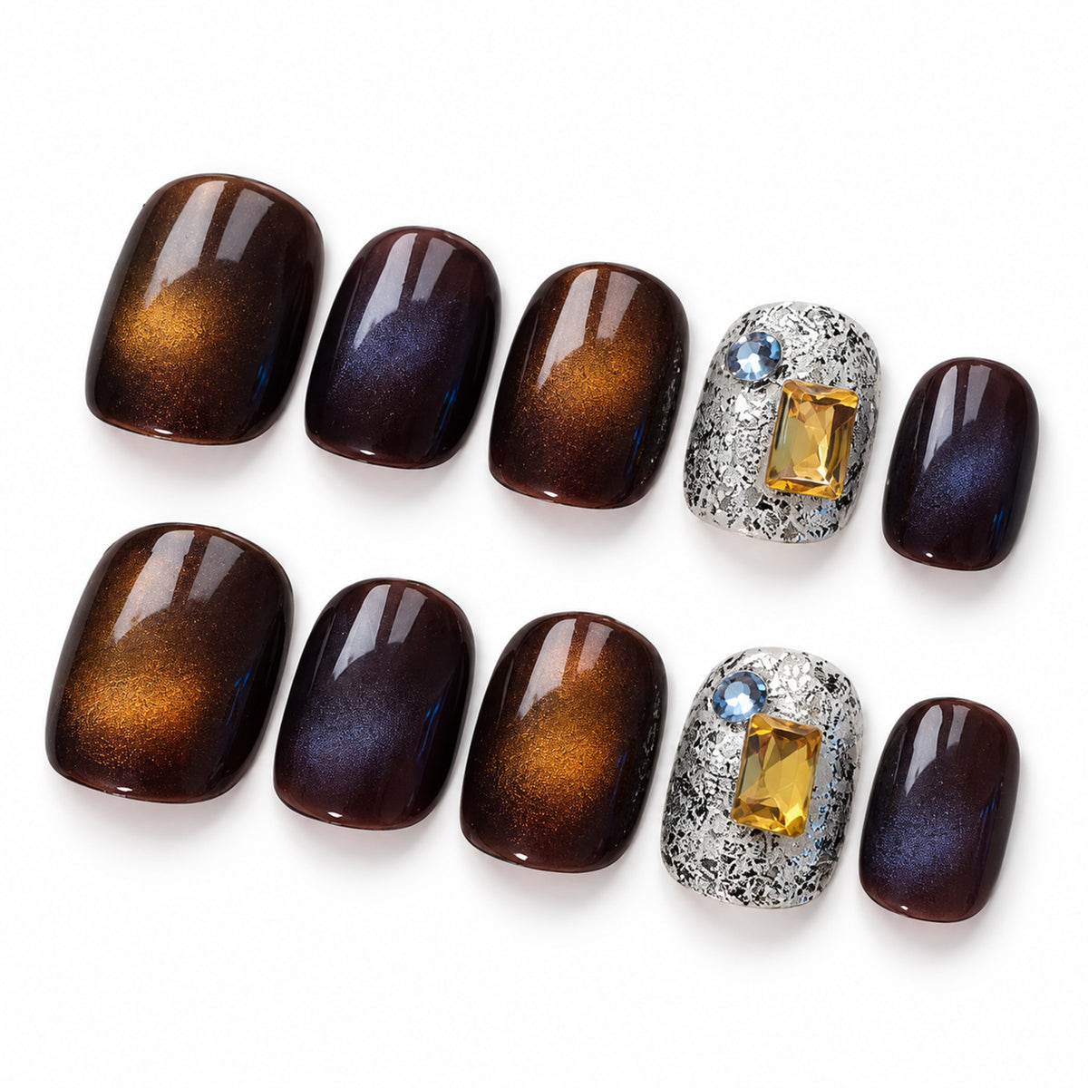 Ten short squoval nail tips on white, with dark glossy nails, amber-coloured highlights and silver-patterned accents with yellow and blue decorations.